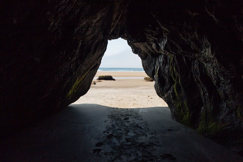 A view of a beach through a cave