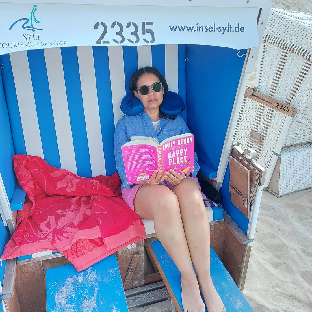 Delise sitting on a beach chair reading Happy Place
