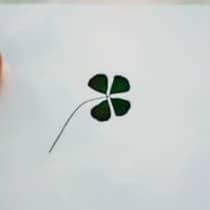 Hand holding a lucky four-leaf clover drawing.