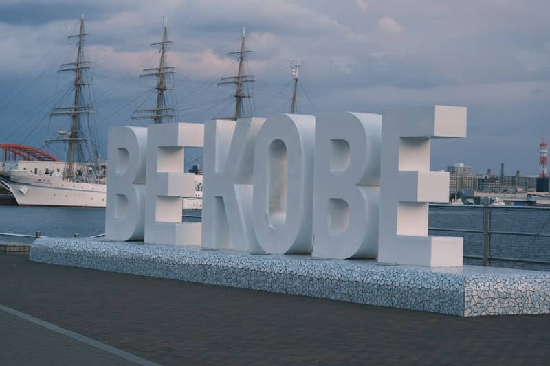Large white be kobe sign with ships in background