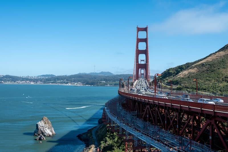 Golden gate bridge spans across blue water under clear sky.