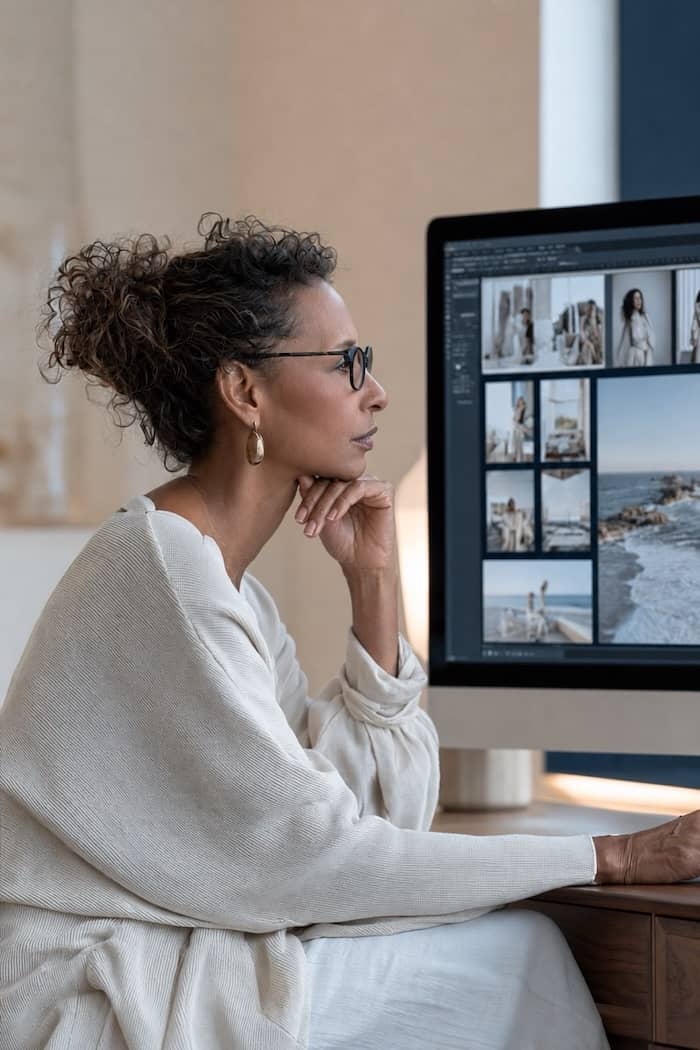 A woman reviewing images for a website on her computer monitor