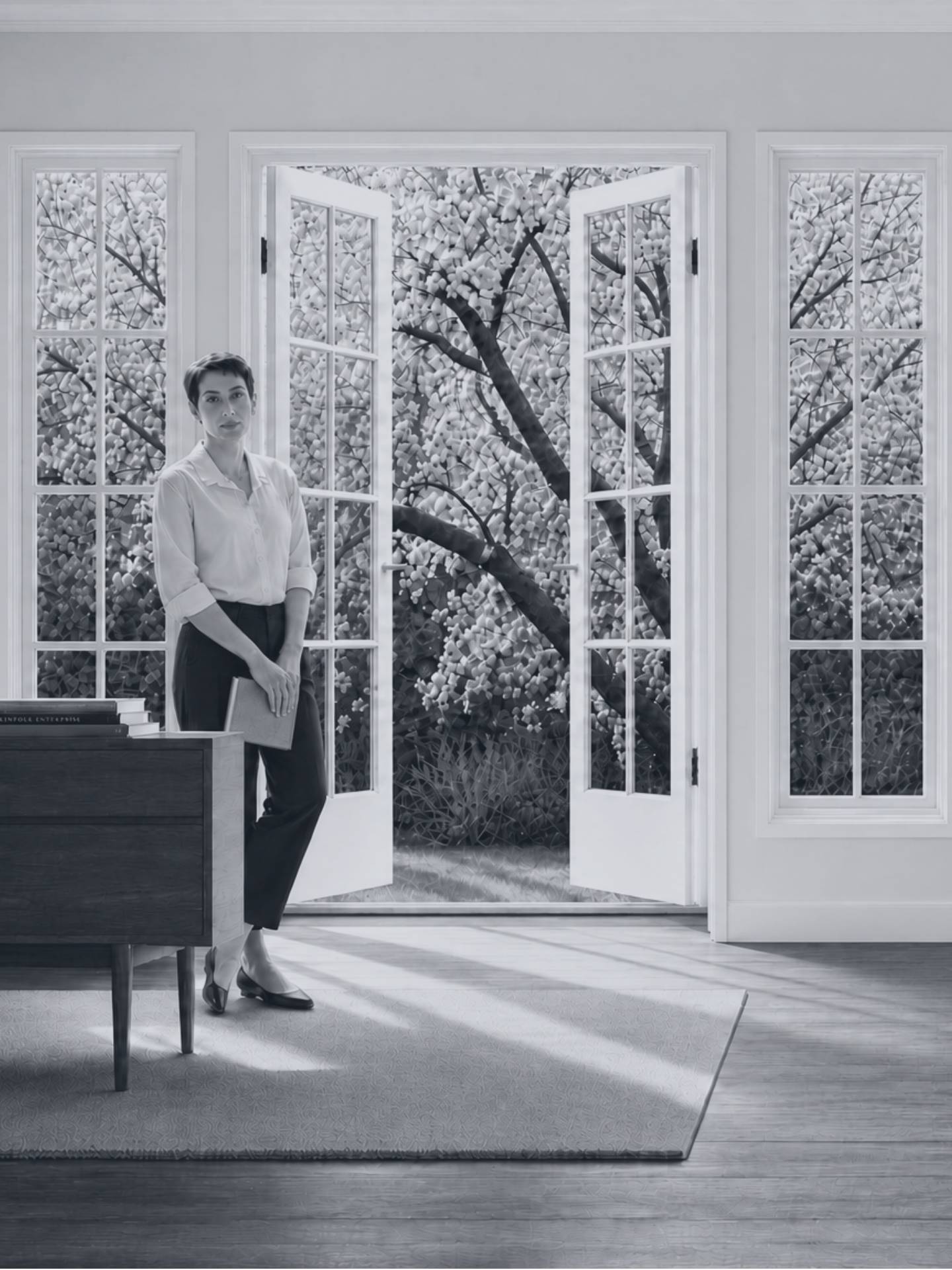 Black and white portrait of a woman standing beside open French doors leading to a blooming tree, symbolizing growth and new beginnings.
