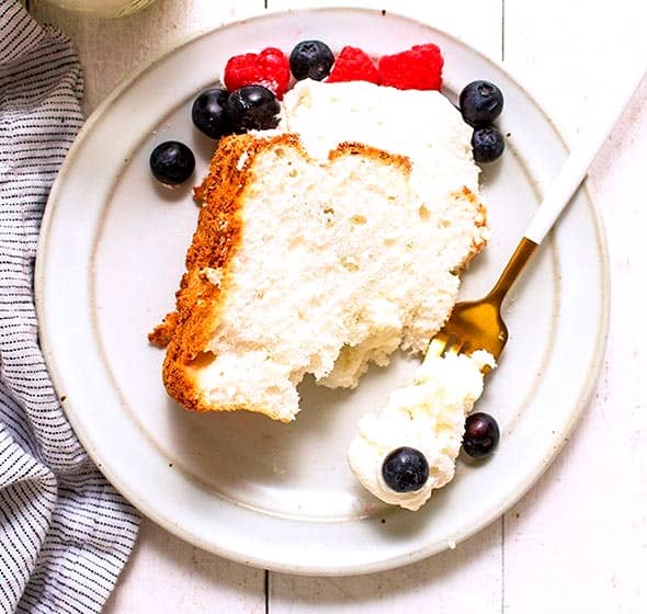slice of angel food cake with berries and whipped cream on plate