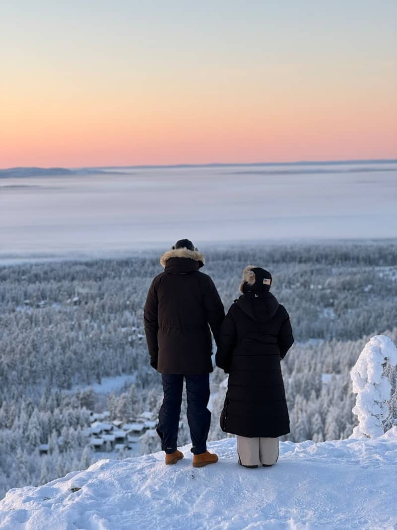 A man and a woman standing on top of a snow covered hill