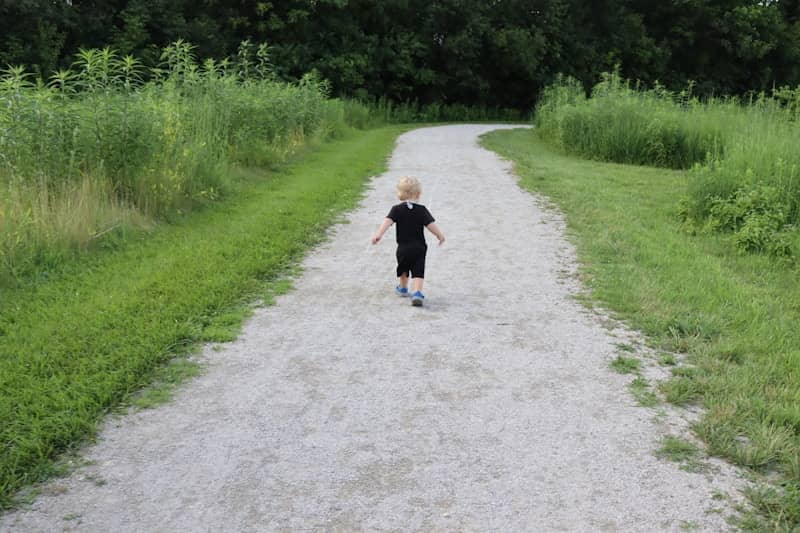 A child walks alone on a gravel path.