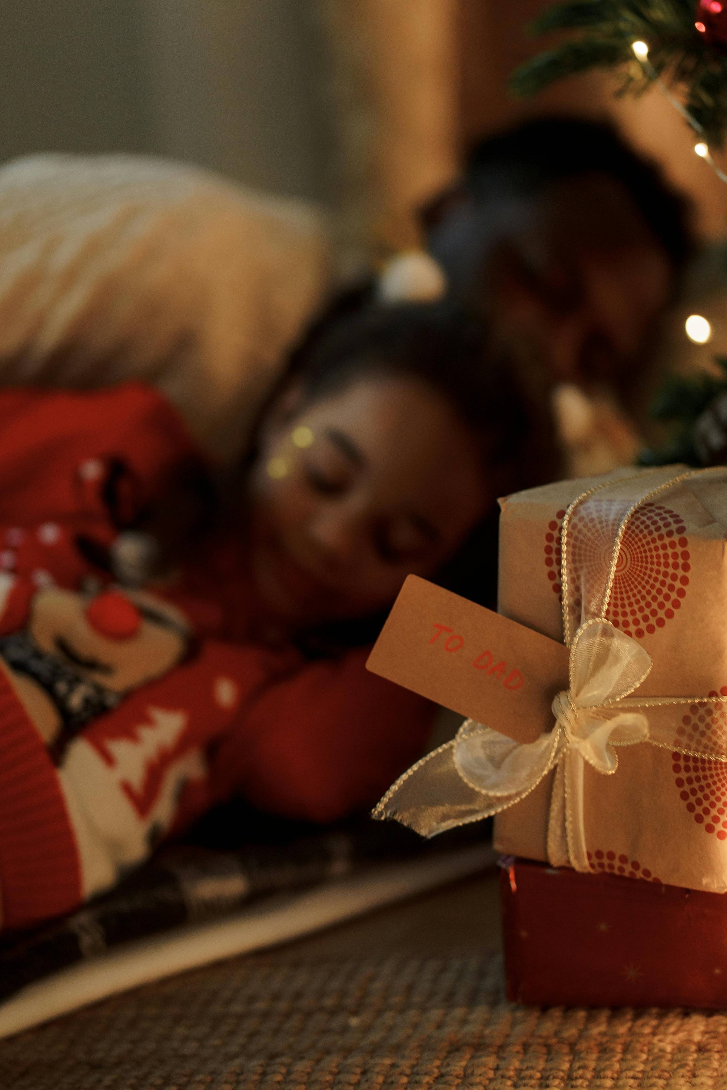 Father and child sleeping in front of the Christmas tree. 