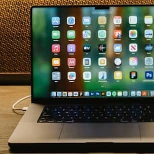 Laptop, camera, and notepad on a wooden desk.