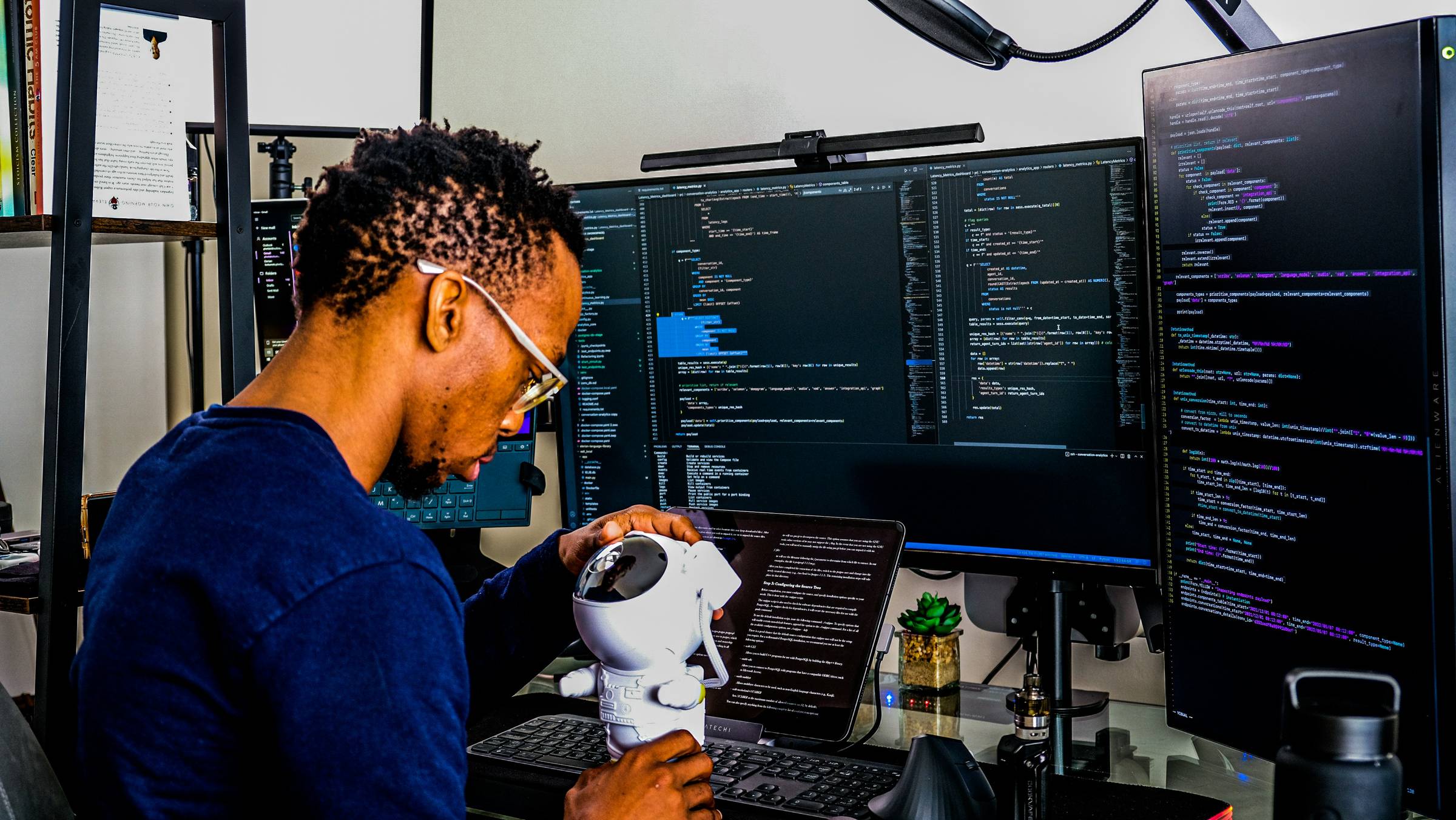A man configuring his Robot in front of 3 screens and a laptop.
