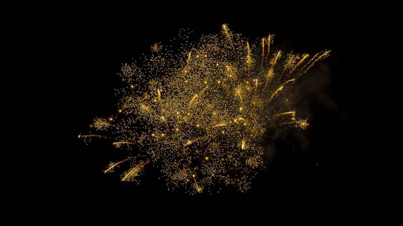 Golden fireworks exploding against a black background