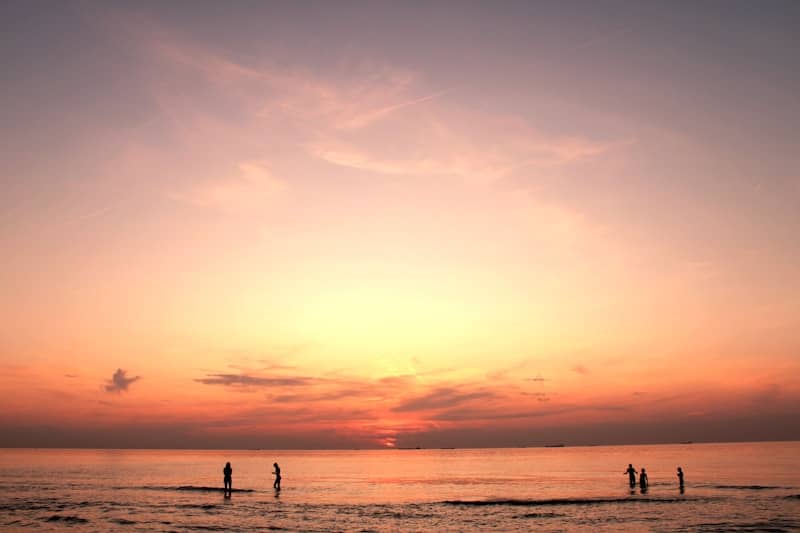 silhouette of people standing on seashore during golden hour