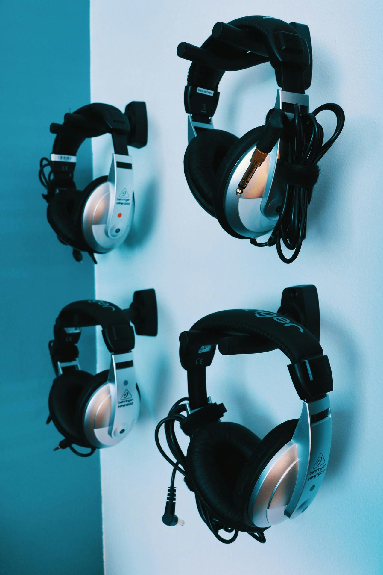 4 pairs of headphones hanging on hooks on a wall