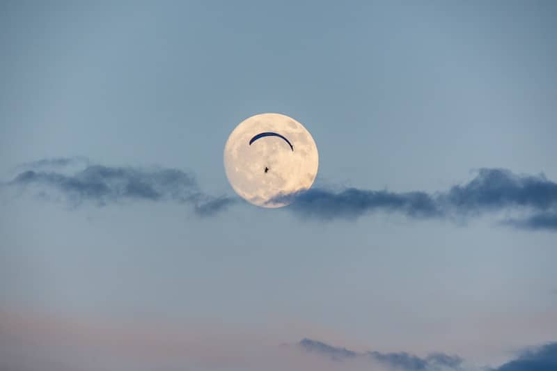 A full moon is seen through the clouds