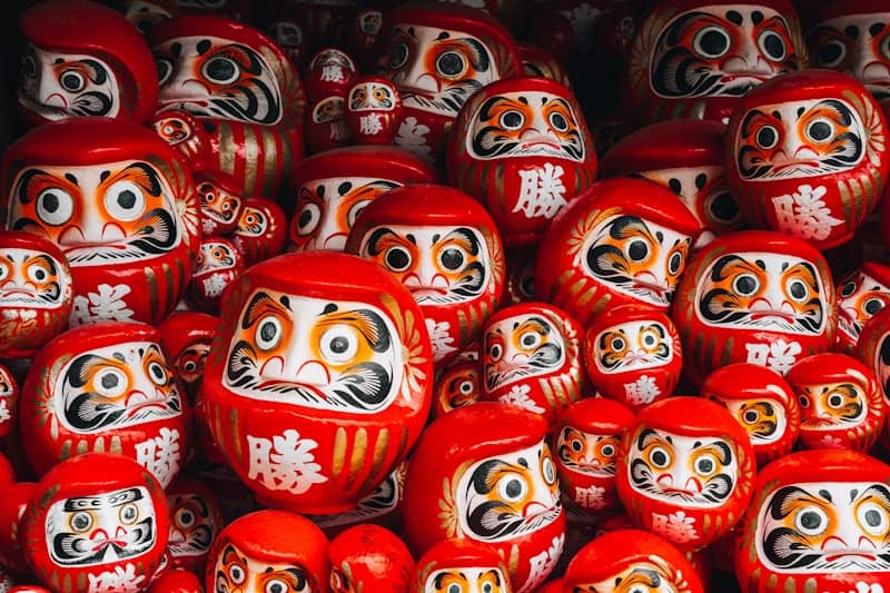 A large collection of red Daruma dolls with painted faces and Japanese characters