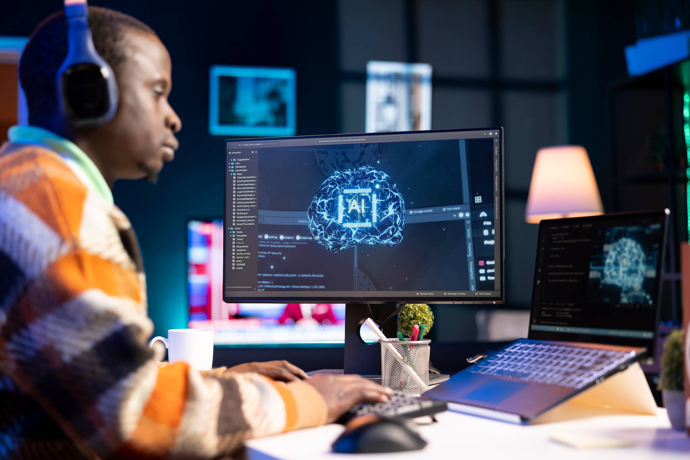 A Black software engineer sitting at a desk, with a computer screen that shows an AI logo overlay on top of code.