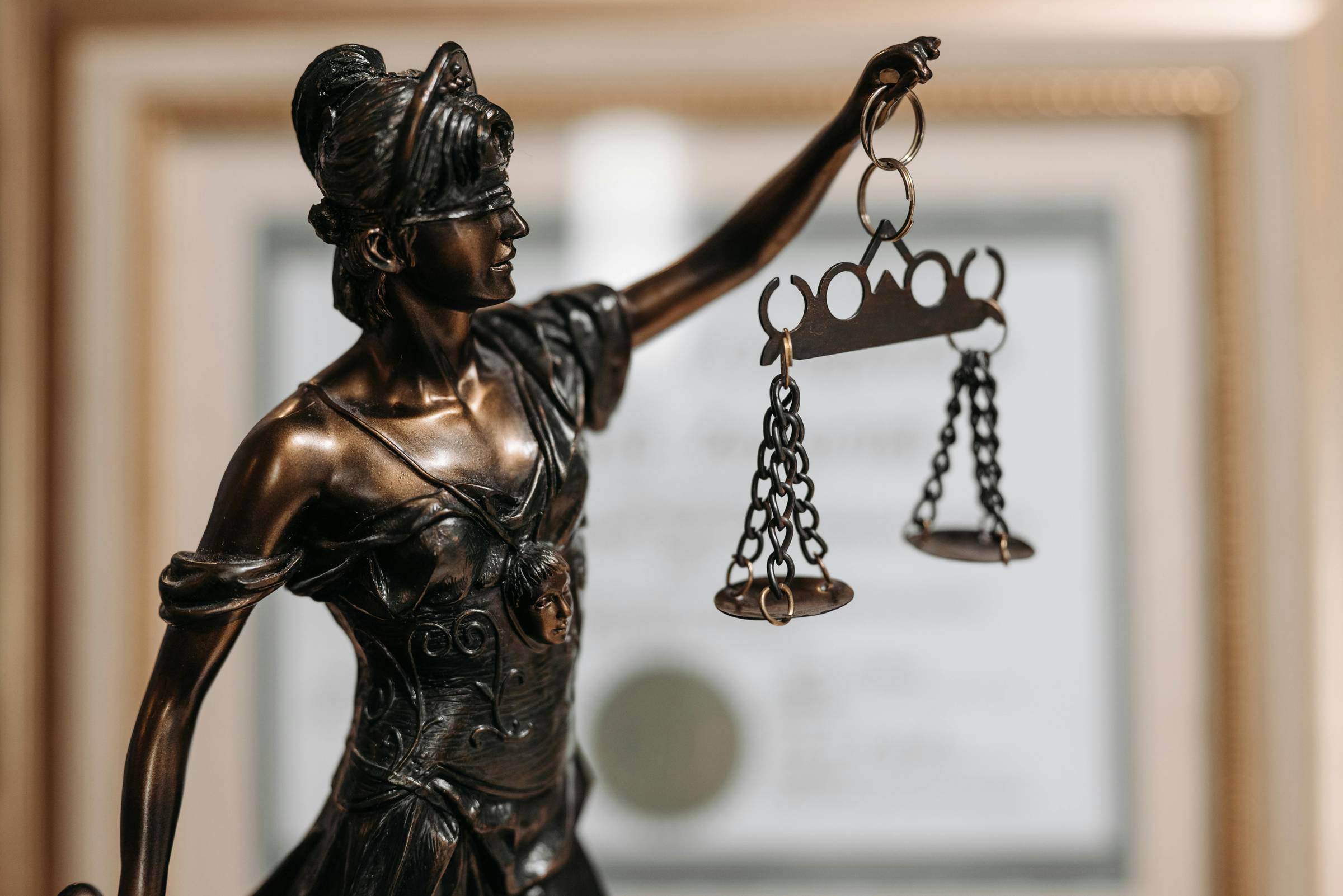 A bronze statue of lady justice with a blindfold, scales and a sword.