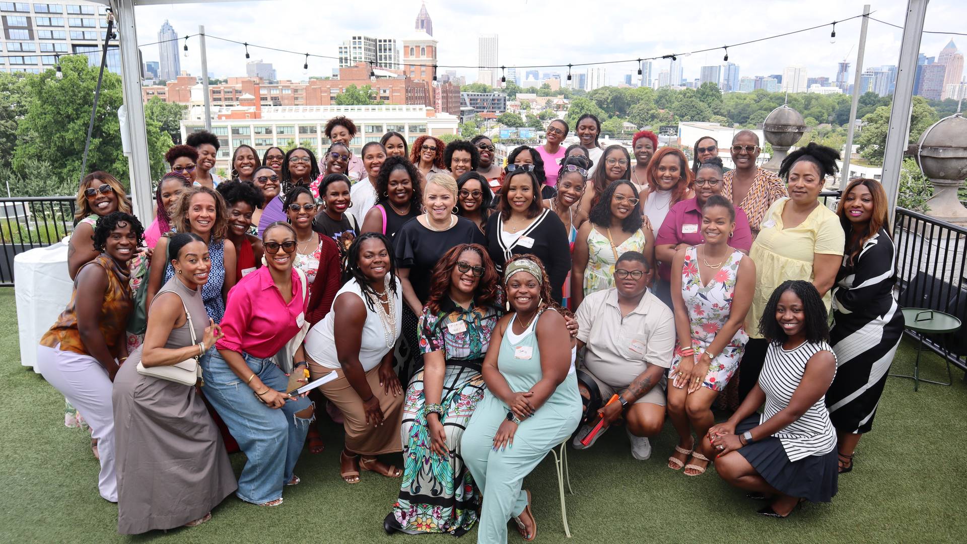Group photo of 40+ Rooted Brunch guests on the Hotel Clermont rooftop with the Atlanta skyline in the background