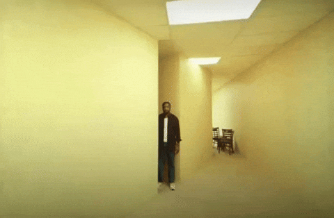 A person standing in a corner of The Backrooms -- a yellow/chartreuse empty space. 
