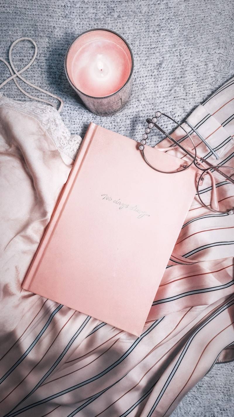 Cozy setup with candle, book, glasses, and clothing.