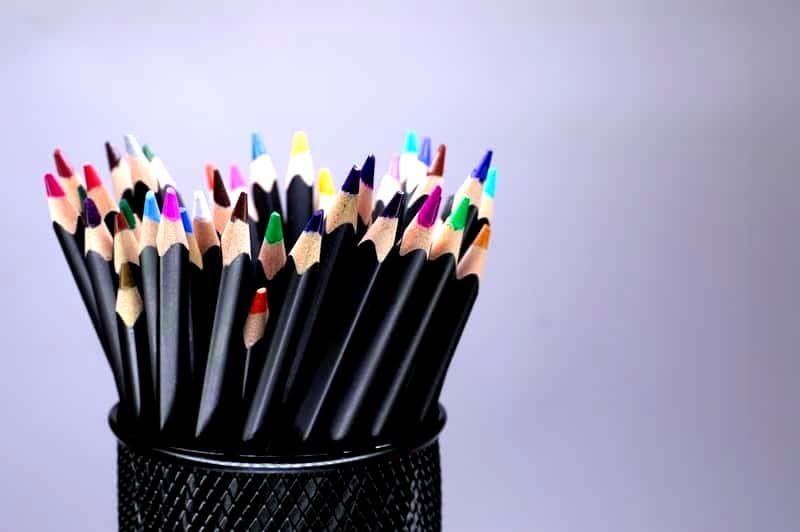 Colored pencils stand in a black holder.