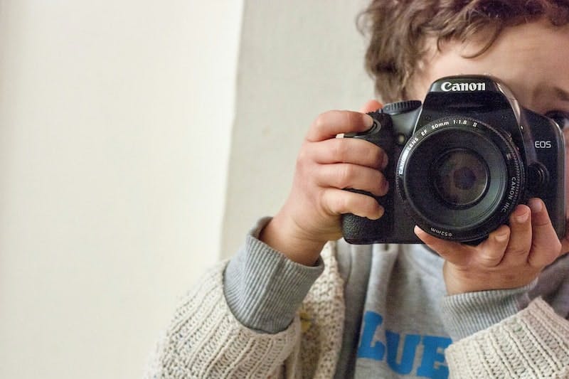 boy holding Canon DSLR camera