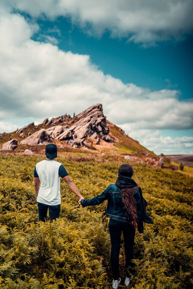 man and woman walking on green grass field during daytime