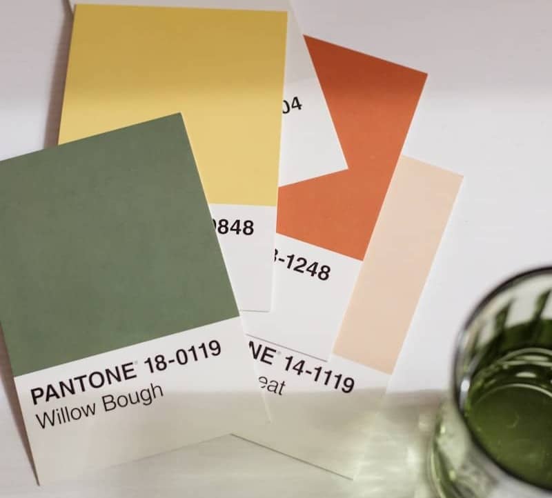 a glass of green paint next to some cards