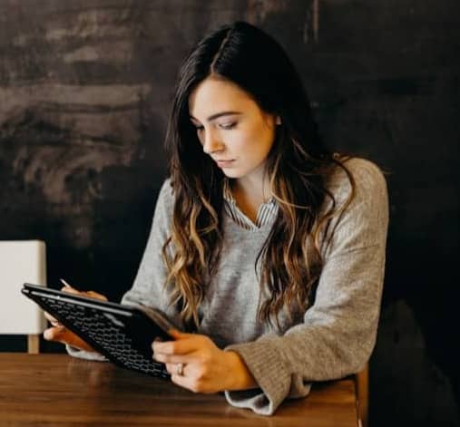 woman wearing white dress shirt using holding black leather case on brown wooden table