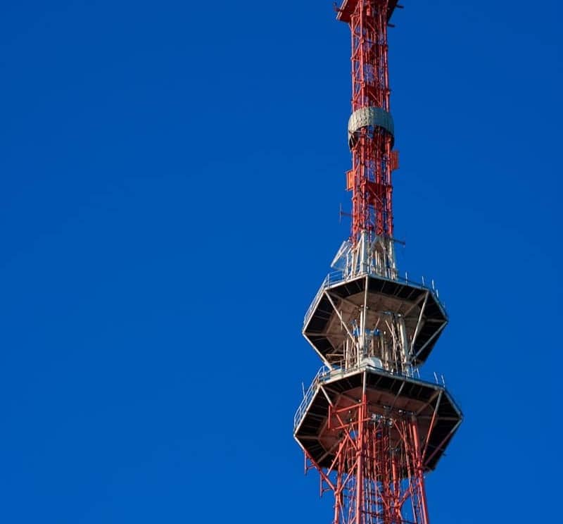 A tall red radio tower against a clear, blue sky.