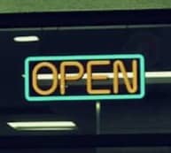 The store is open, showcased by a neon sign.