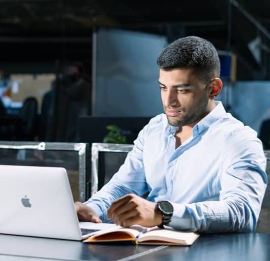 A man sitting at a table using a laptop computer