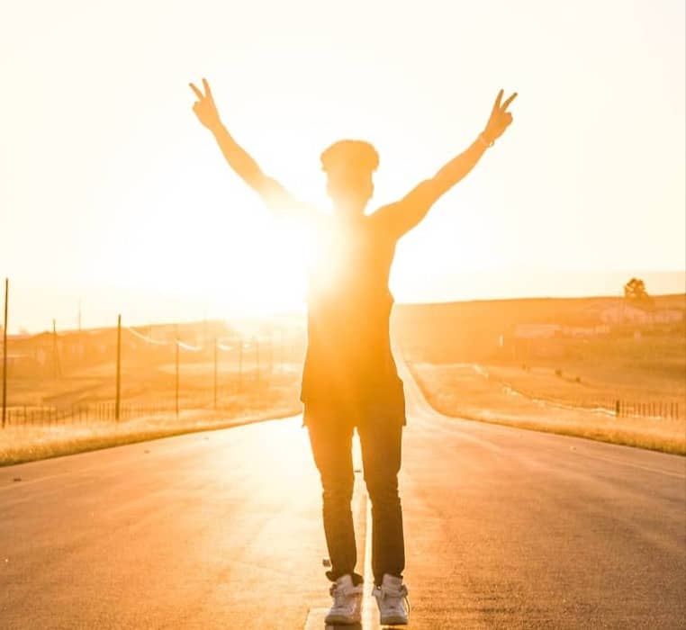 person raising both hands doing peace sign hand gesture on road during daytime