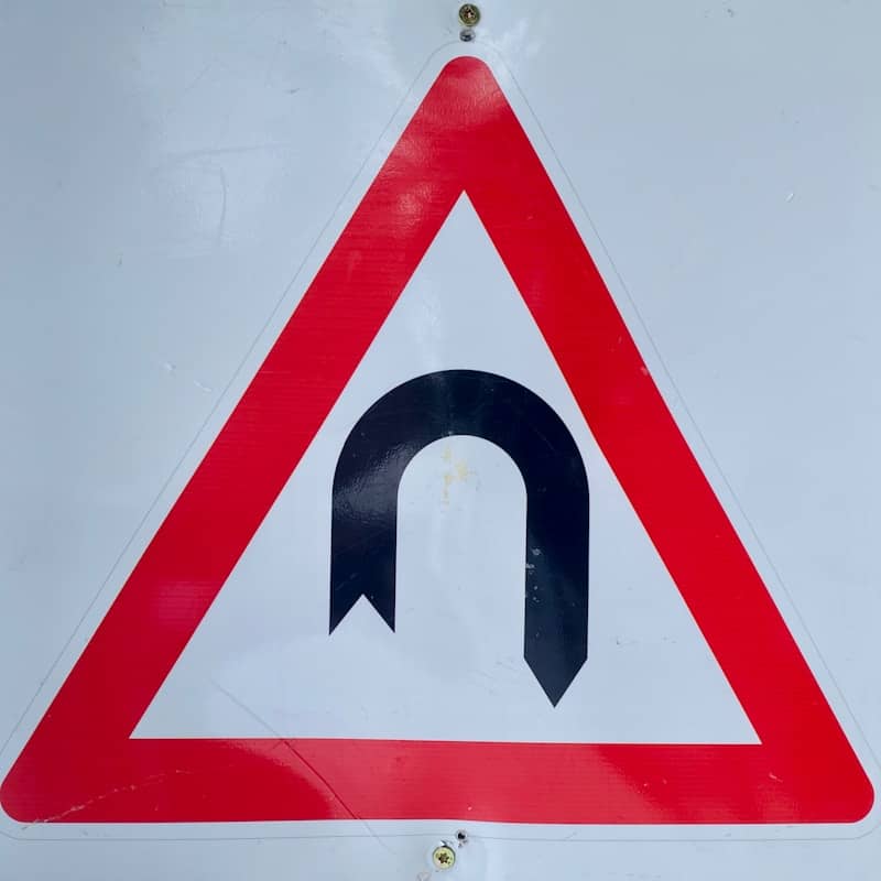 a red and white sign with a black arrow on it