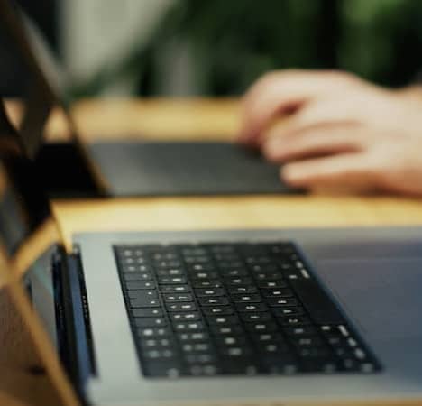 A person typing on a laptop on a wooden table