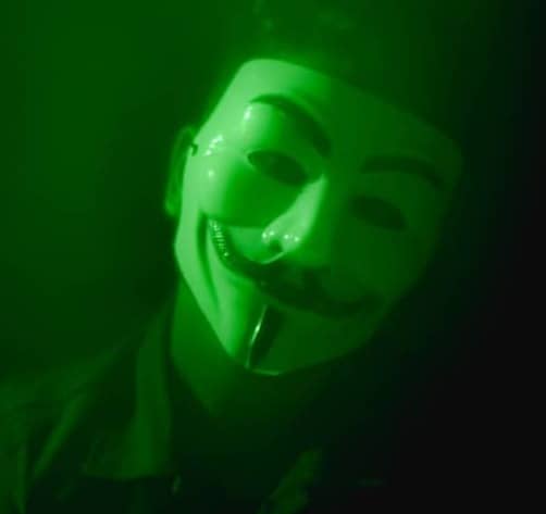 a man wearing a green mask in the dark