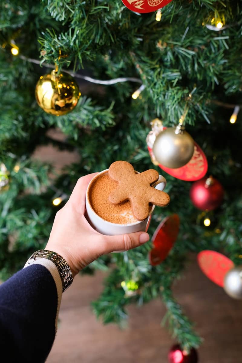 Coffee with gingerbread man by Christmas tree