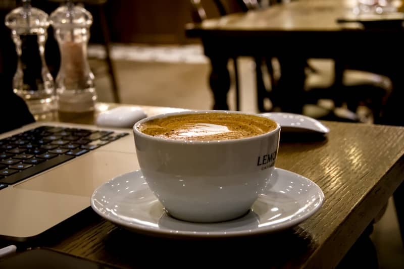 A cup of coffee sits on a wooden table.