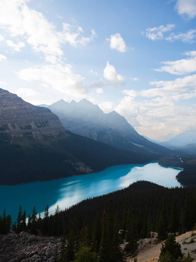 Turquoise lake surrounded by dark pine forest and mountains.