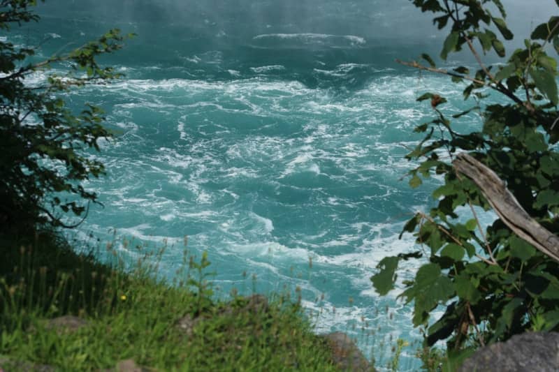 Raging, turquoise water with trees on either side.