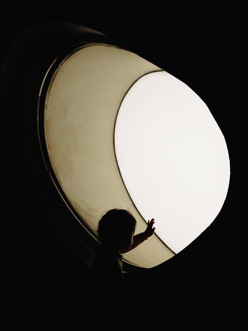 Silhouette of a child reaching towards a bright light.
