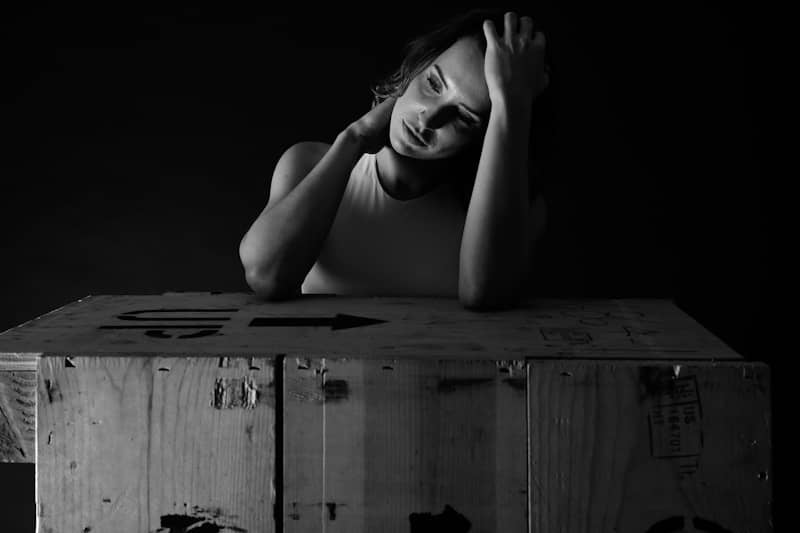 Woman resting head on hands behind wooden crate