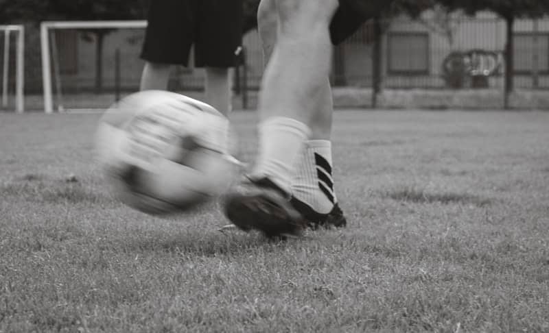 A person kicking a soccer ball on a grassy field.