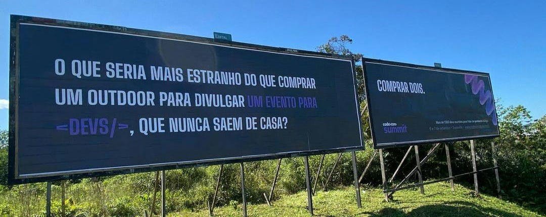 Foto de dois outdoors, um escrito O que seria mais estranho do que comprar um outdoor para diulgar um evento para devs, que nunca saem de casa? e o outro escrito Comprar dois.