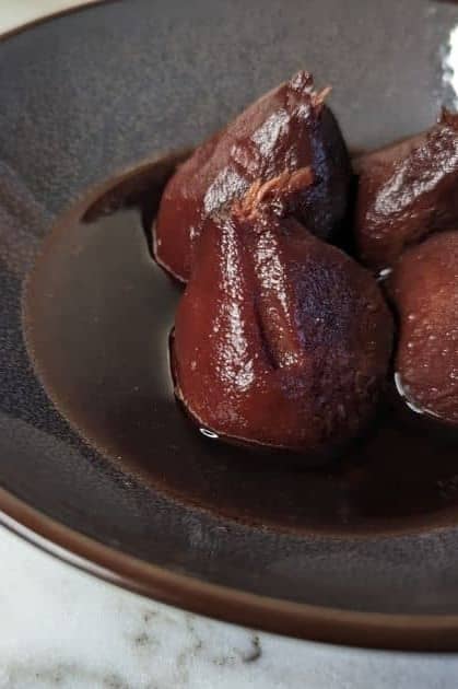 fully cooked, dark red stewed pears served in a brown bowl