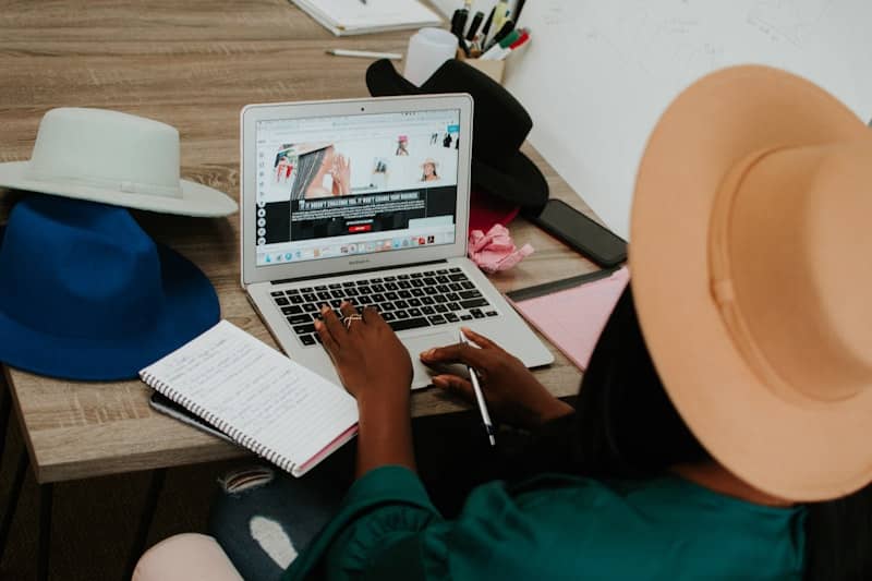 woman sits on padded chair while using MacBook during daytime