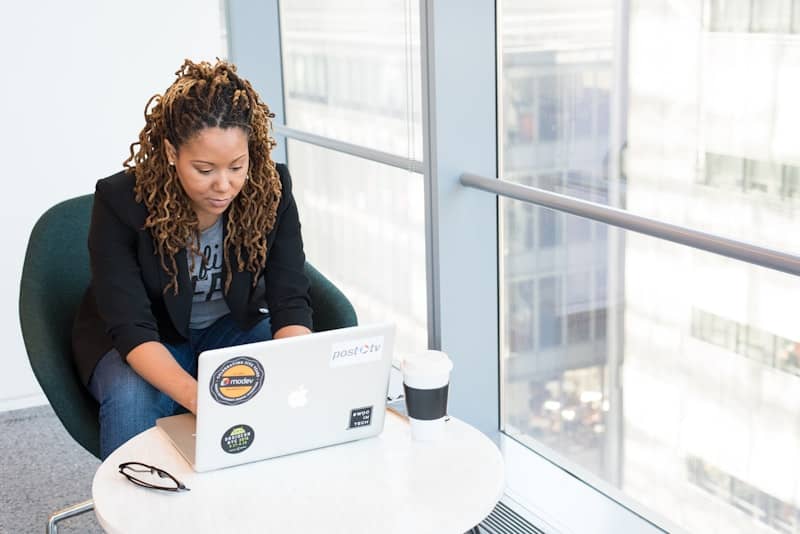 person using macbook air on white table