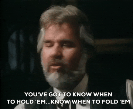 Gif of Kenny Rogers, a white man with short grey hair and a beard, from the music video for his song "The Gambler" with the words 'You've got to know when to hold 'em, know when to hold 'em"