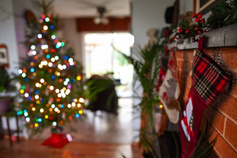 A christmas tree in a living room next to a fireplace