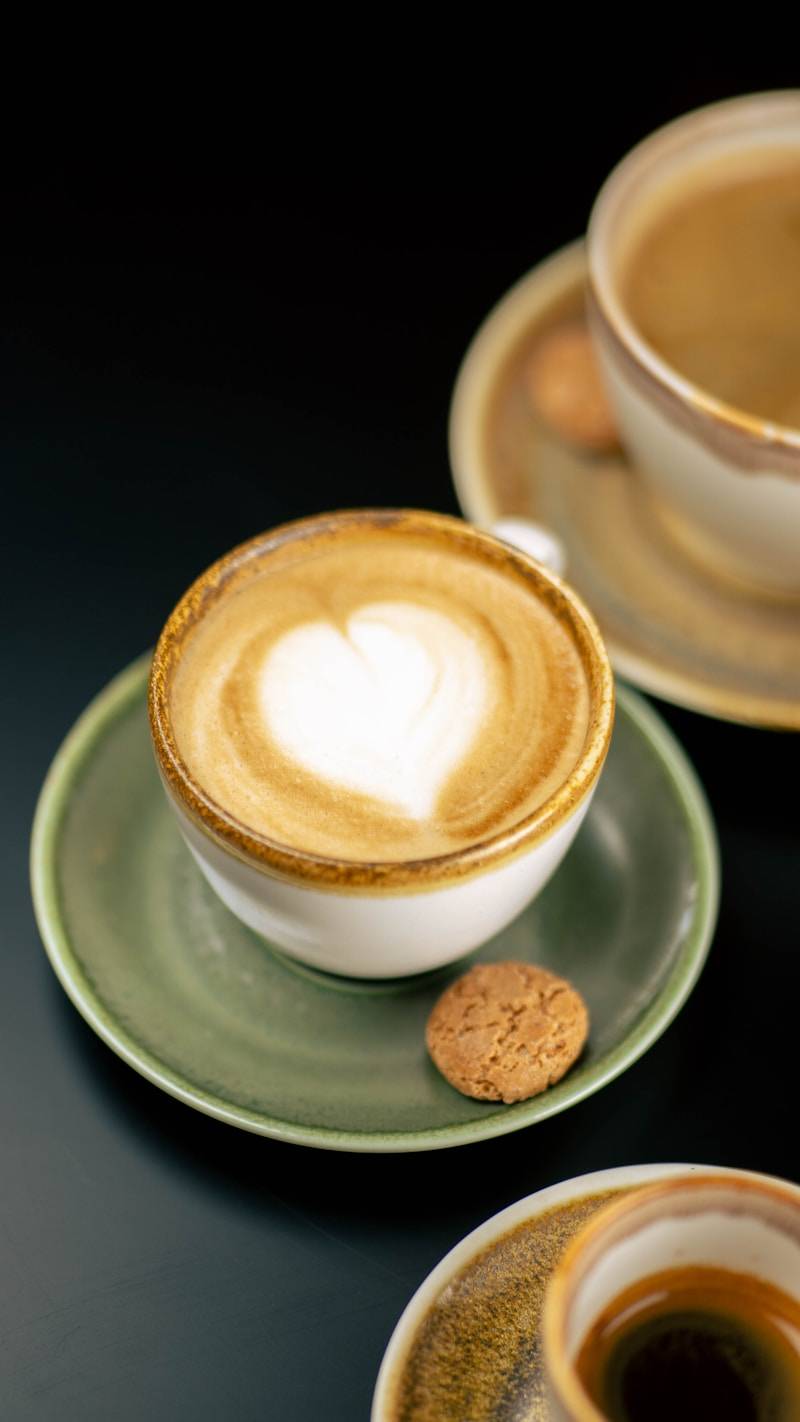 Heart latte art in a coffee cup with a cookie.