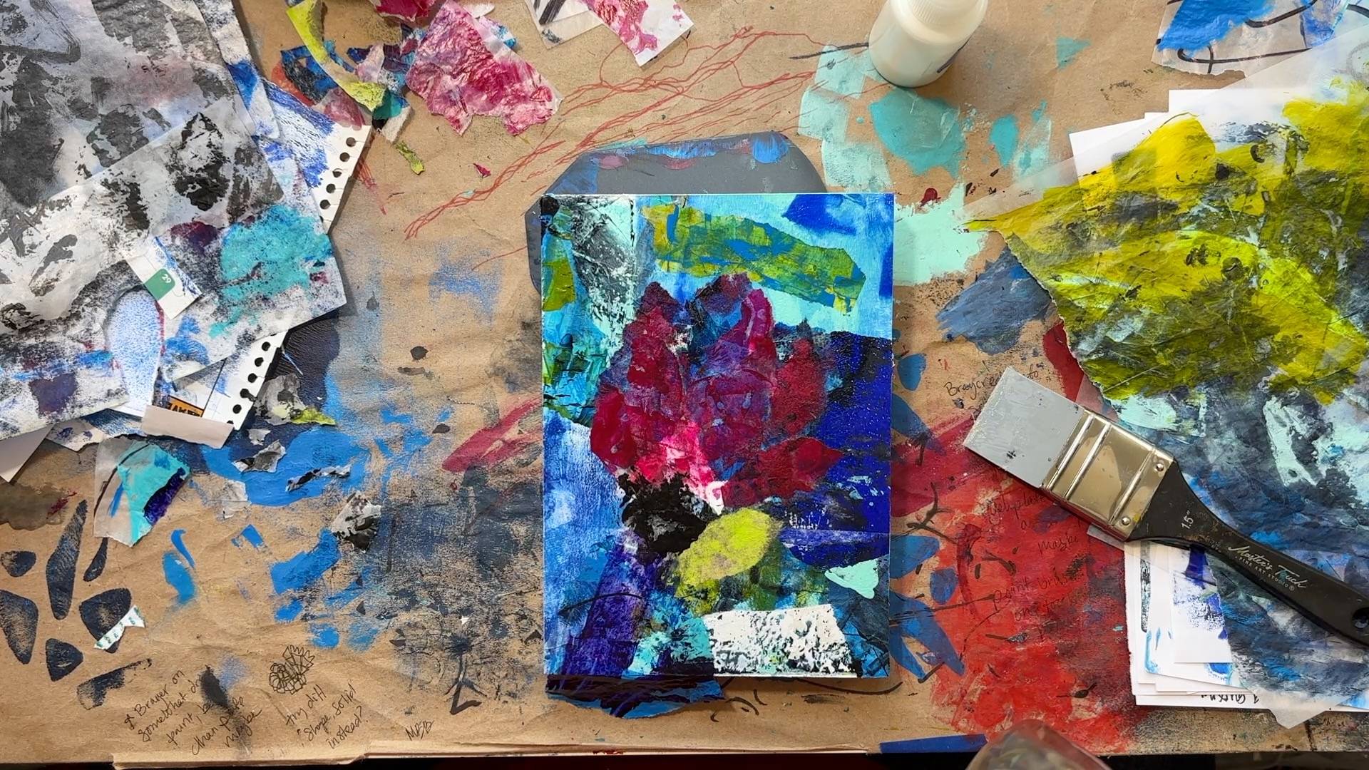 Top down view of messy desk with floral collage panel in the middle